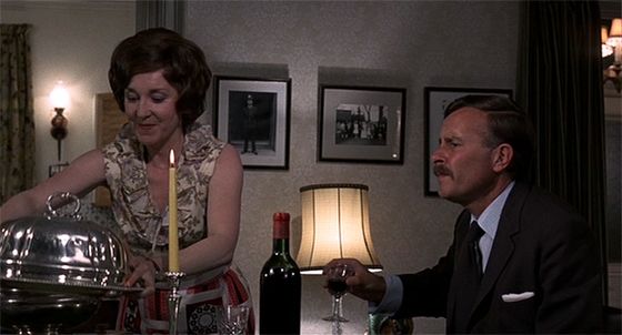 Mrs. Oxford serves a meal while the Inspector talks murder